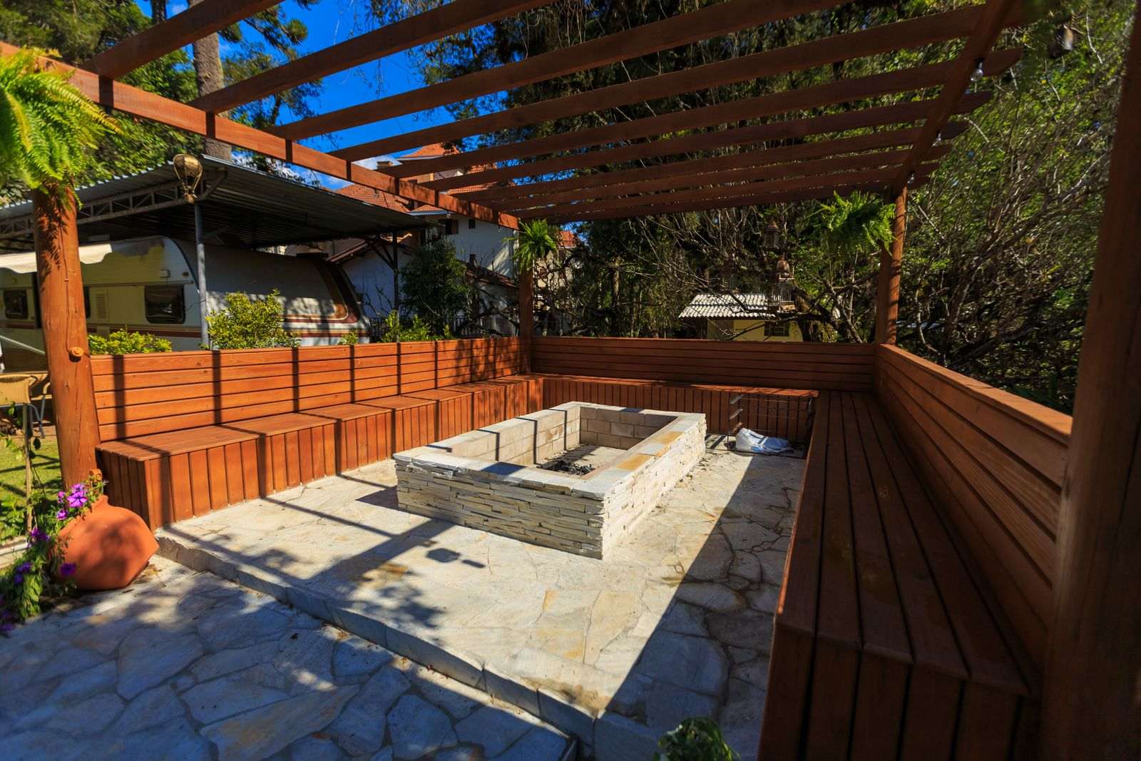 A finished flagstone patio with an outdoor fire pit, benches and a wooden pergola